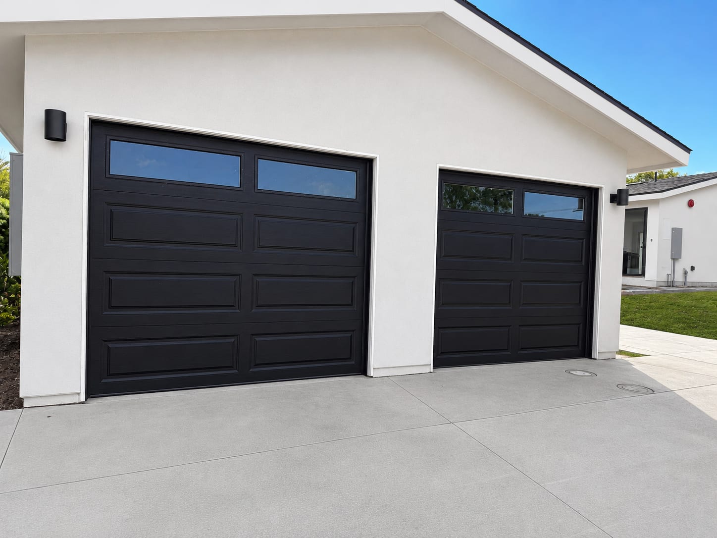 Two black insulated Clopay garage doors on a modern white San Diego home