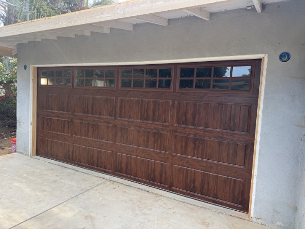 Clopay Gallery Collection long-panel garage door in a walnut woodgrain finish with divided-light windows, installed on a light stucco home in Encinitas, CA by A Reliable Garage Door